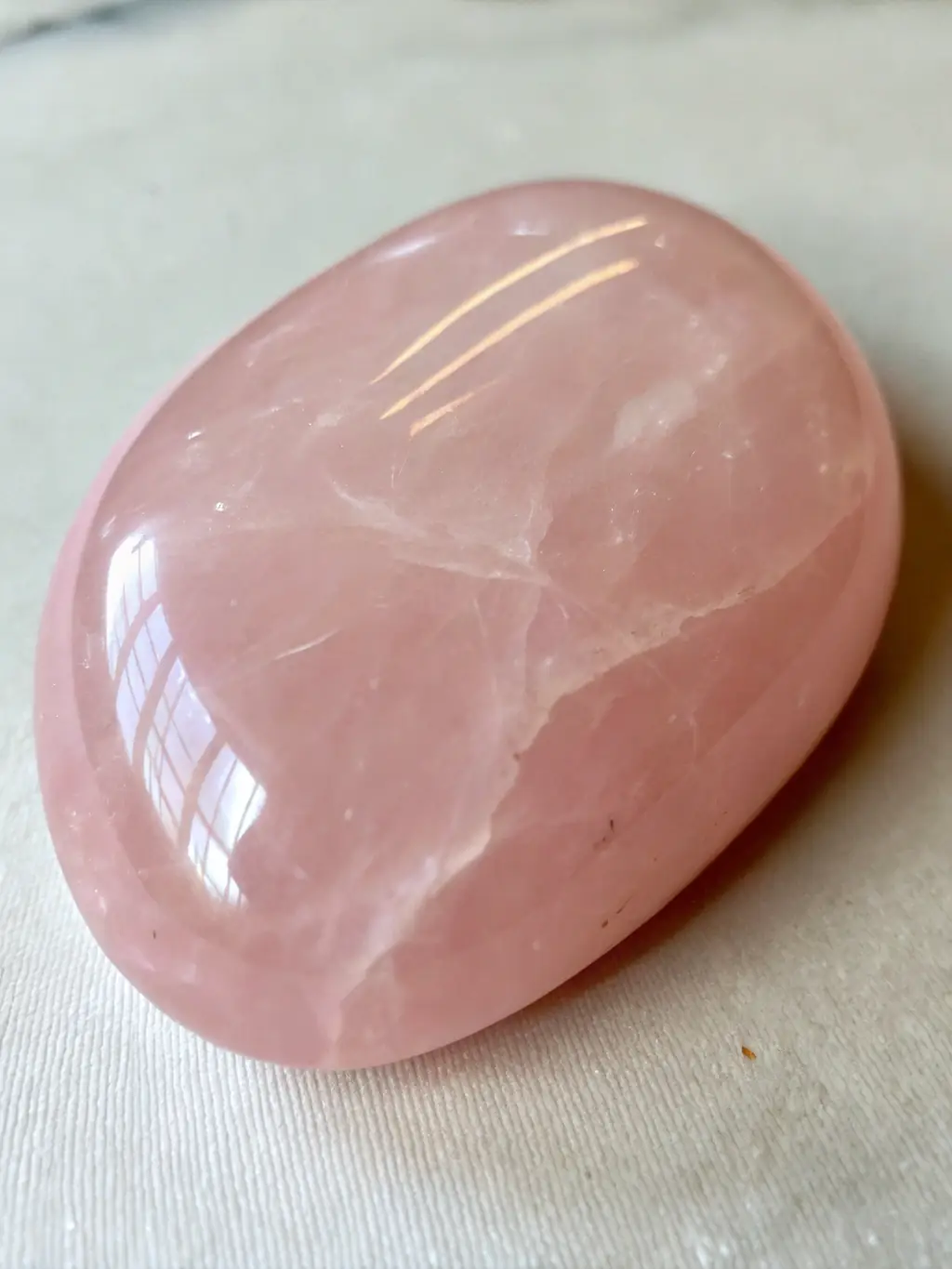 A Rose Quartz Point, polished to a smooth finish, highlighting its soft pink hue and natural clarity, emphasizing its gentle and calming appearance.